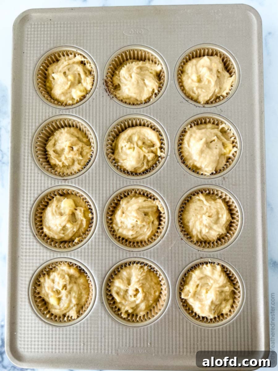 A muffin pan neatly filled with banana bread muffin batter, ready for baking.