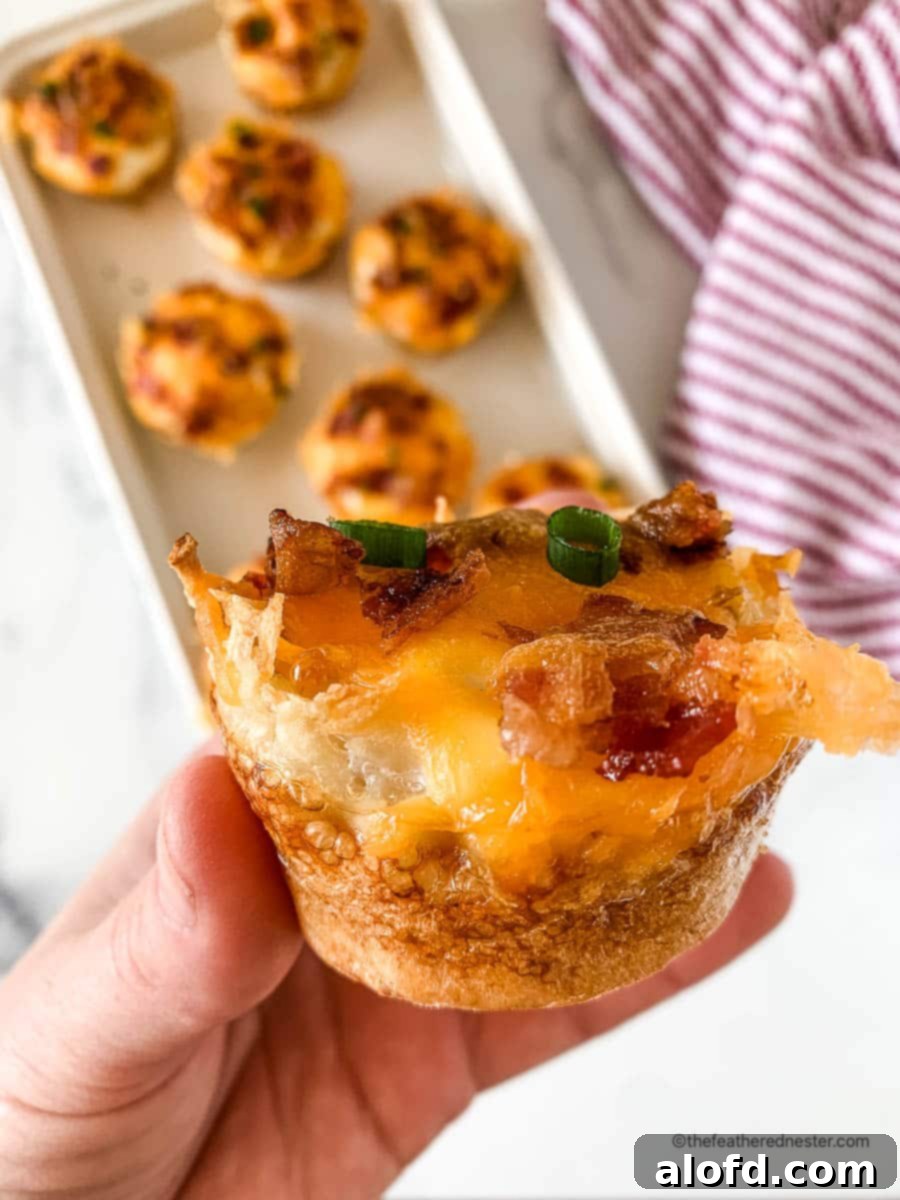 Crispy Hash Brown Egg Cups 3 A hand holding a hash brown breakfast cup, and a tray full of baked egg cups in the background.