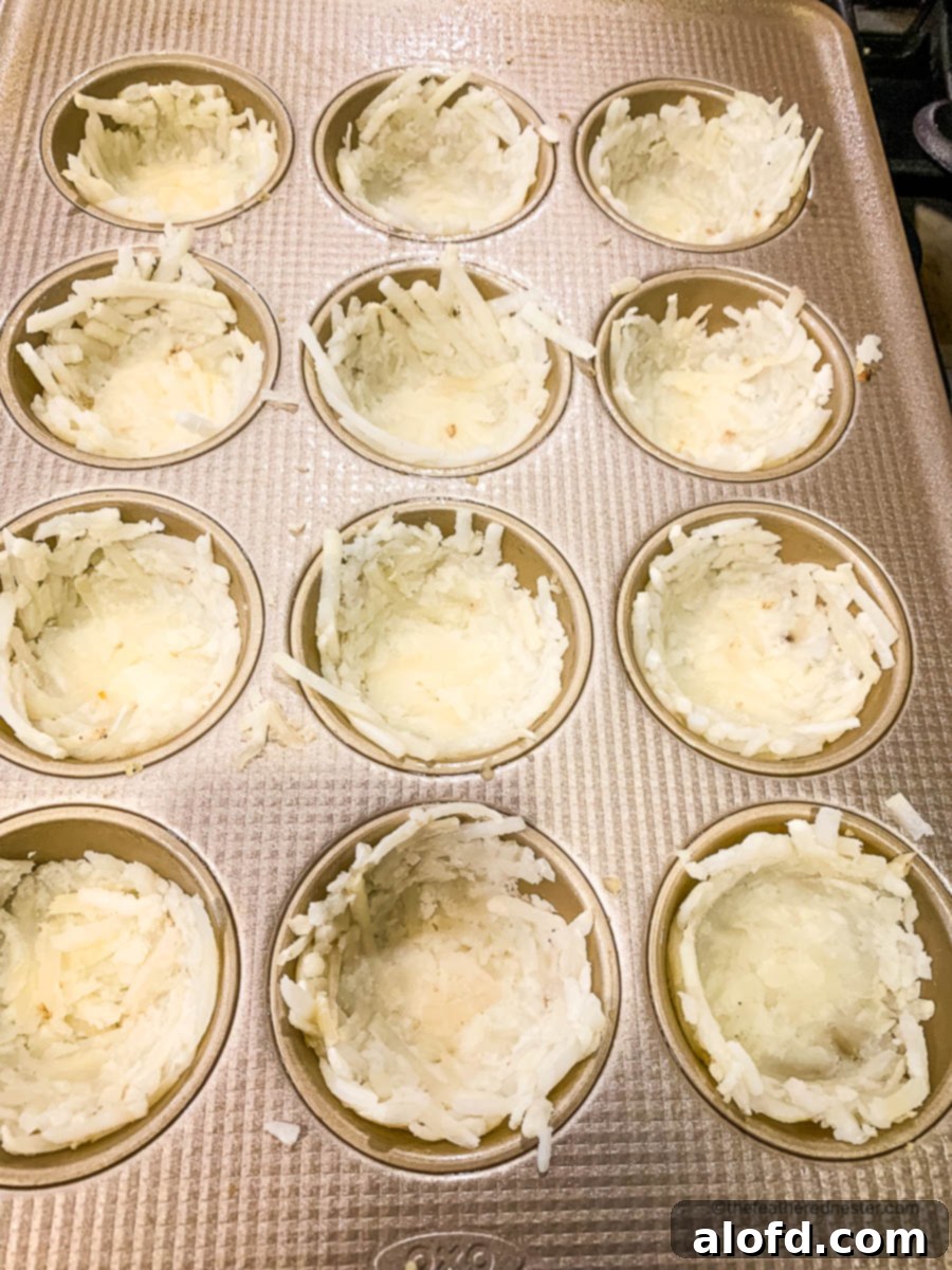 Crispy Hash Brown Egg Cups 8 raw shredded potatoes pressed into a muffin pan.