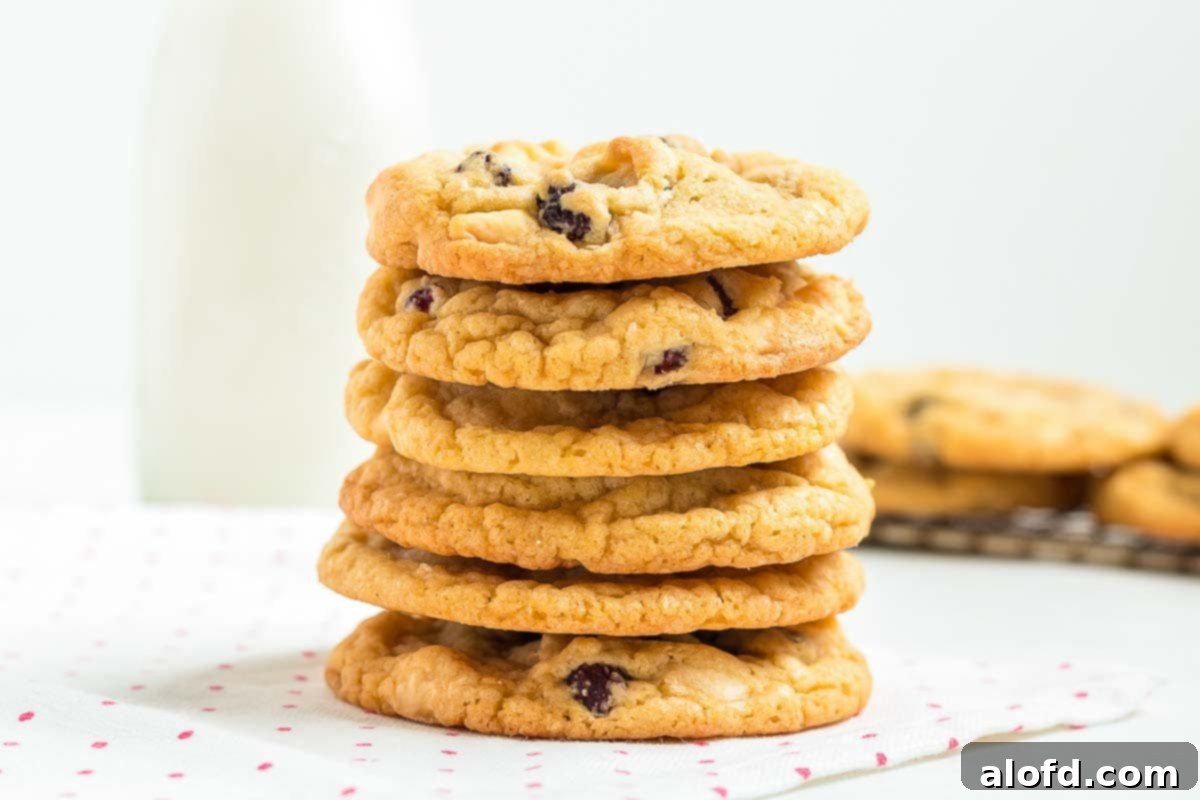 A charming stack of white chocolate raspberry cookies sits next to a bottle of milk, embodying a perfect sweet snack moment.
