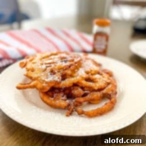 A white plate with Bisquick funnel cake and a red striped cloth and a cinnamon powder bottle at the back.