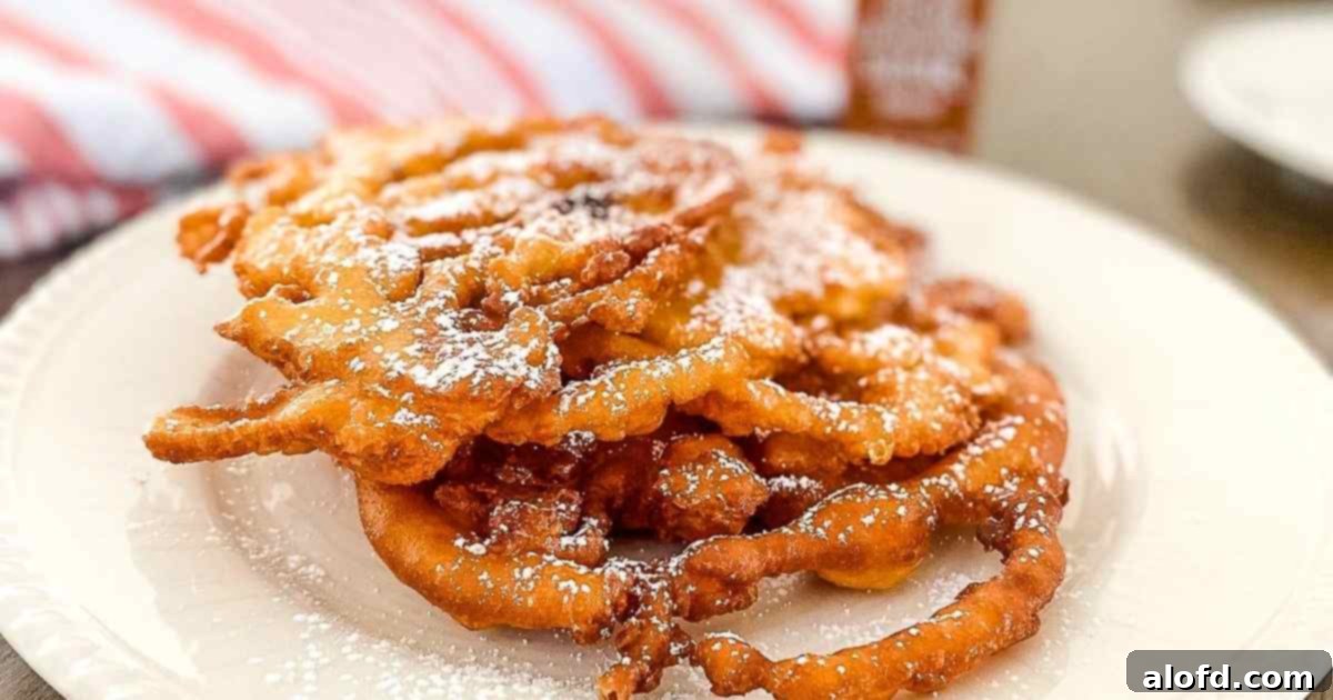 A white plate holding a freshly made Bisquick funnel cake, with a striped red cloth visible in the background, inviting you to indulge.