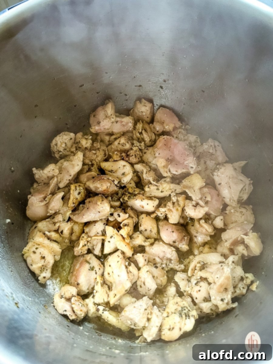 Speedy Instant Pot Pozole 7 Cooked, diced chicken in an Instant Pot, showing a golden brown color from sautéing.