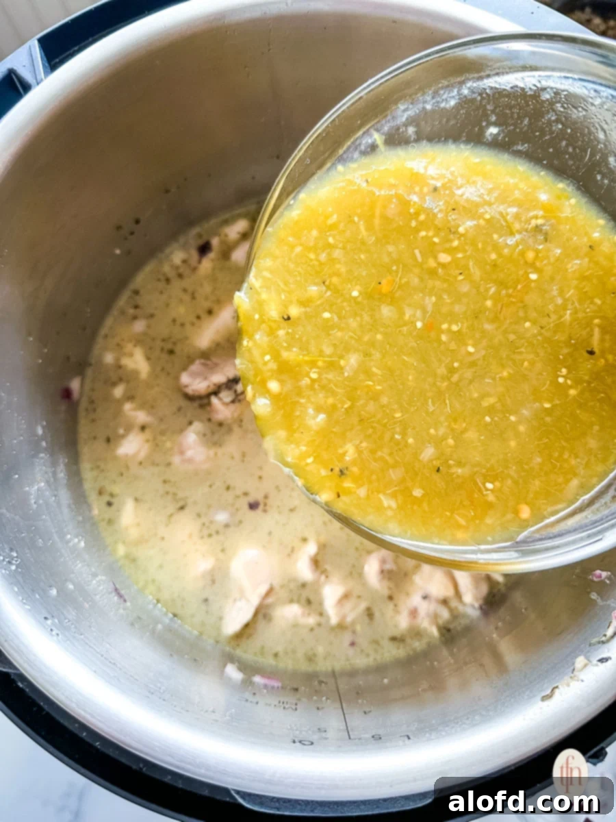 Speedy Instant Pot Pozole 8 Chicken broth being poured into an Instant Pot containing sautéed chicken and onions, initiating the deglazing process.