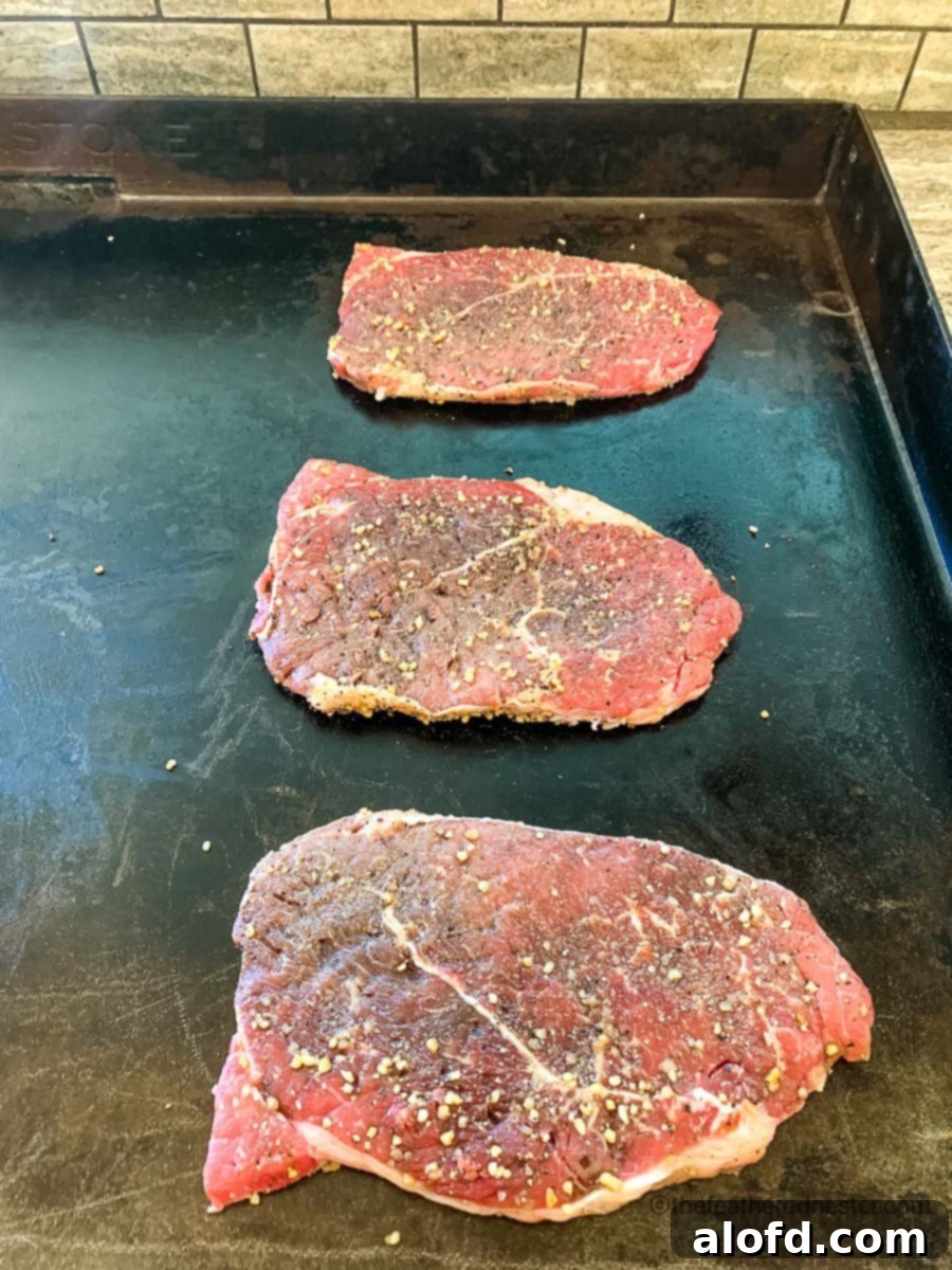 Sizzling Steaks on the Blackstone Griddle 5 Cooking the raw steaks on the griddle.