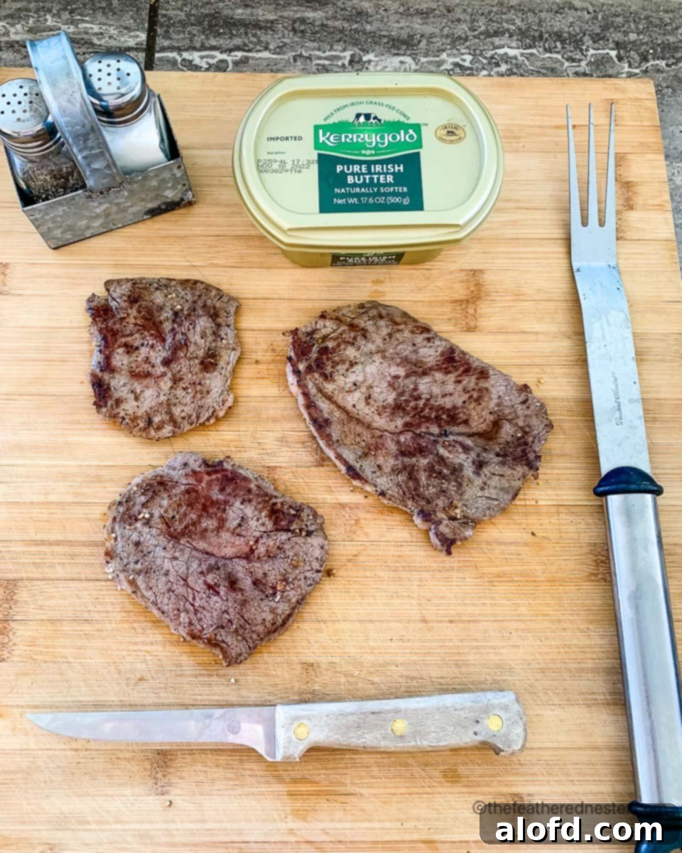 Sizzling Steaks on the Blackstone Griddle 7 Cooked Blackstone Steaks on a wood board with Butter, Salt, Pepper, Knife and a Fork.