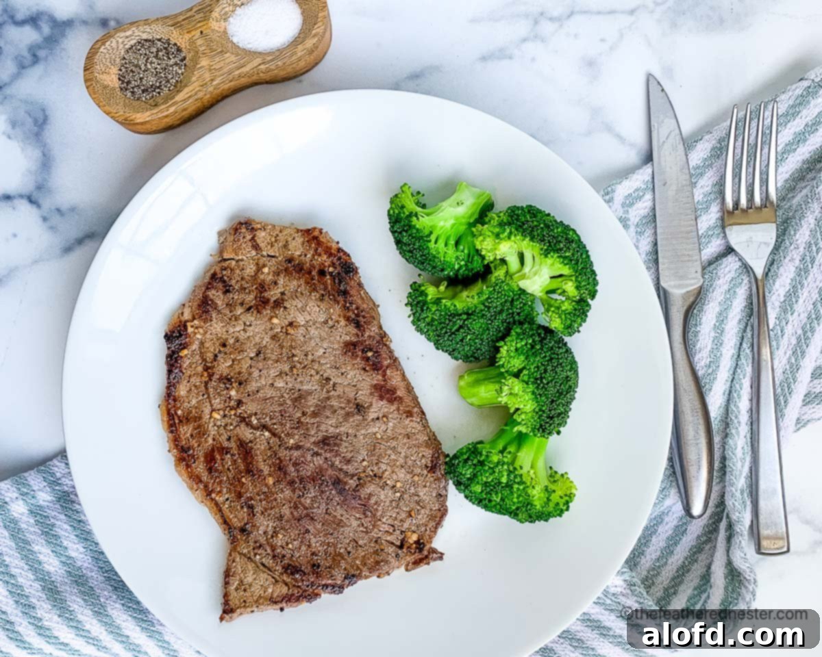 Sizzling Steaks on the Blackstone Griddle 8 Hibachi steak with broccoli on a white plate with silverware and a blue and white napkin.