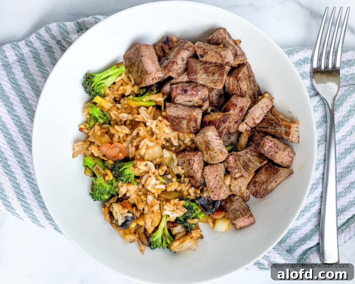 Sizzling Steaks on the Blackstone Griddle 9 Chopped teppanyaki steak with fried rice on a white plate with silverware.