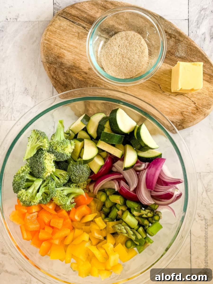Vibrant Blackstone Veggies 6 A colorful medley of chopped vegetables in a clear glass bowl, accompanied by a wooden cutting board with a bowl of spices and a pat of butter, all prepared for cooking Blackstone vegetables.