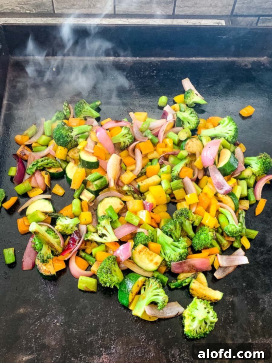 Vibrant Blackstone Veggies 7 Close-up of chopped vegetables sizzling on a Blackstone flat top grill, showcasing the cooking process.