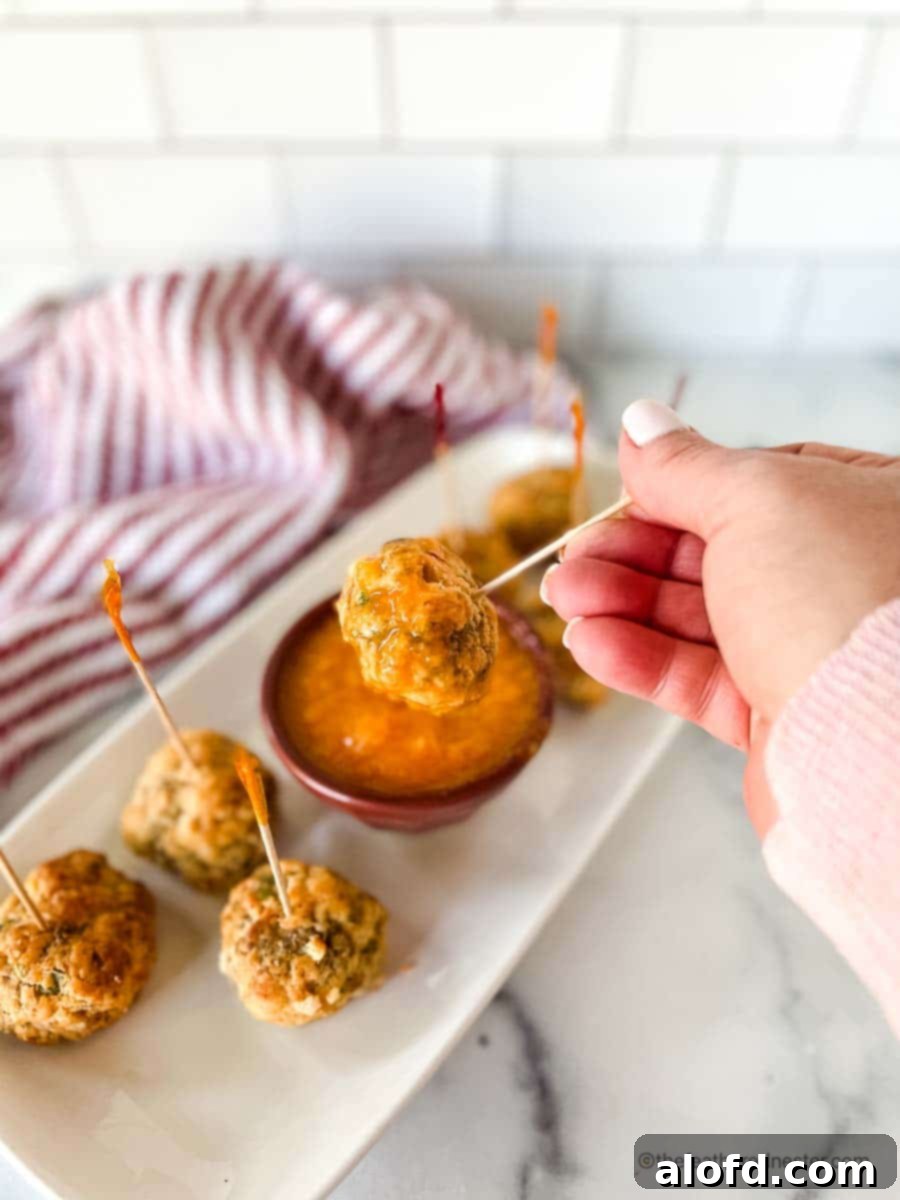 Sweet mango sauce and pimento cheese balls being dipped into the sauce, highlighting its vibrant color and luscious texture.