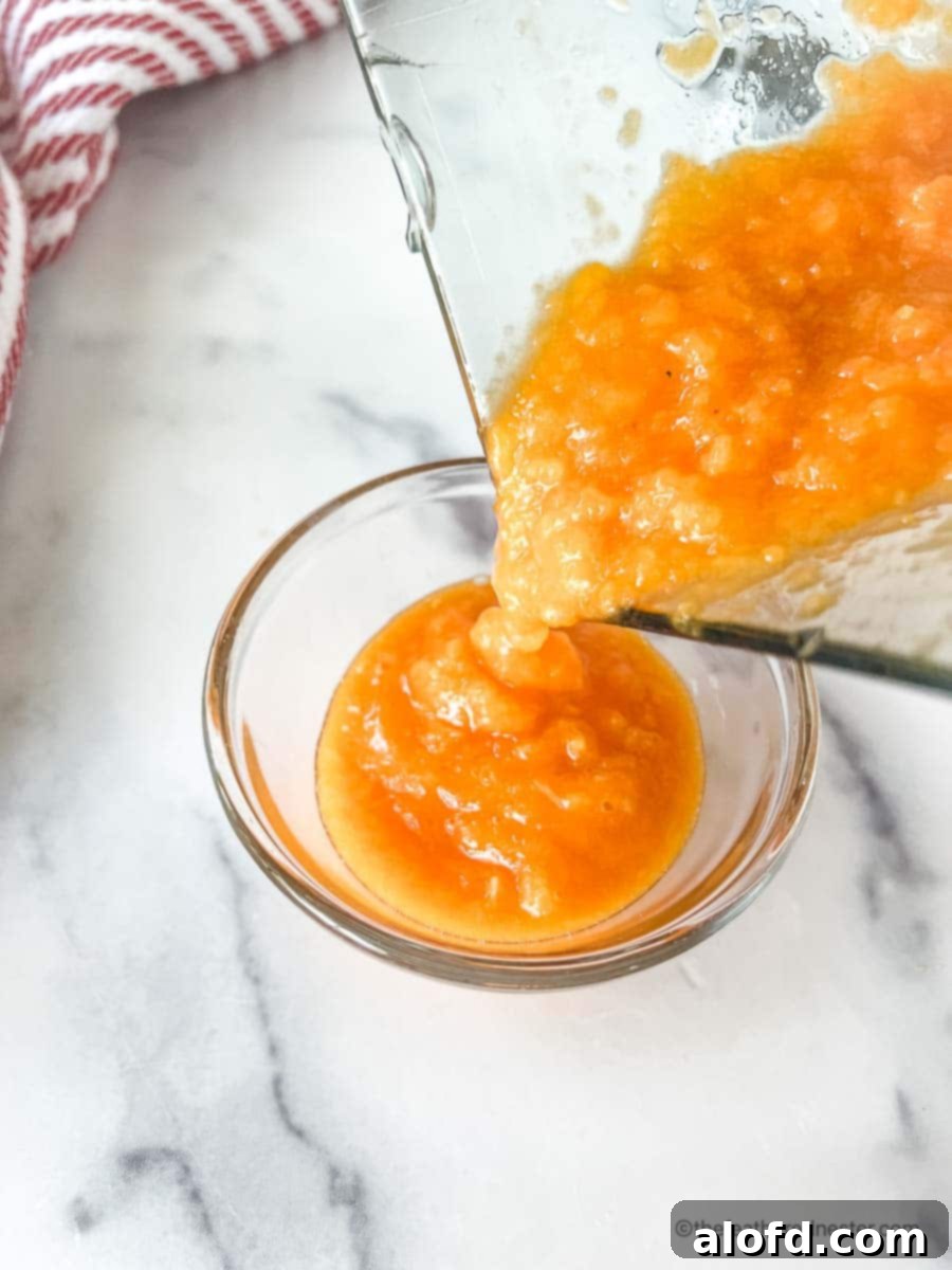 Pouring smooth, sweet mango chili sauce directly from the blender into an elegant serving dish, indicating it's perfectly ready to be enjoyed.