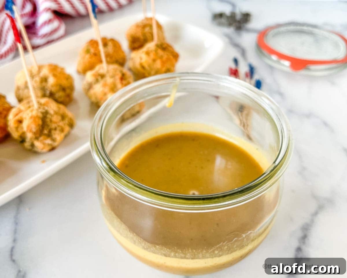 Zesty Honey Mustard Sauce 9 A Weck jar of hot and sweet mustard sauce with savory sausage balls in the background.