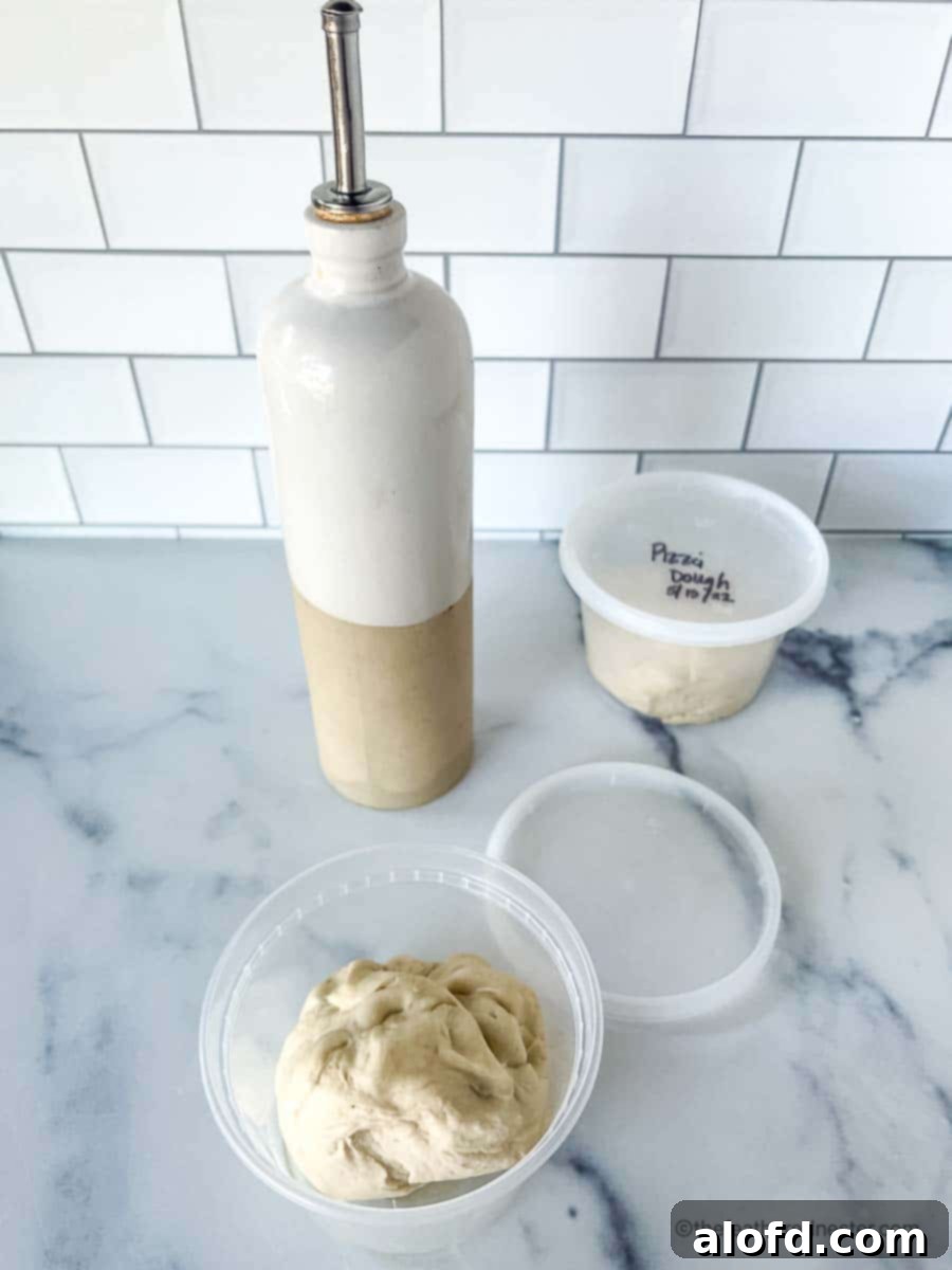Mastering Pizza Dough Freezing for Future Feasts 2 An open container of frozen pizza crust sitting on a countertop with a bottle of olive oil in the background.