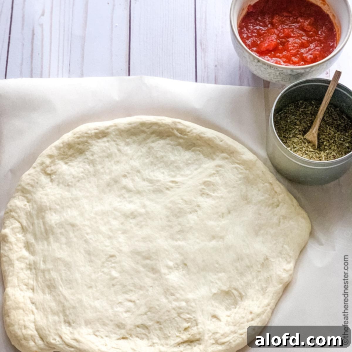 Mastering Pizza Dough Freezing for Future Feasts 8 A rolled out circle of pizza dough laid on parchment paper.