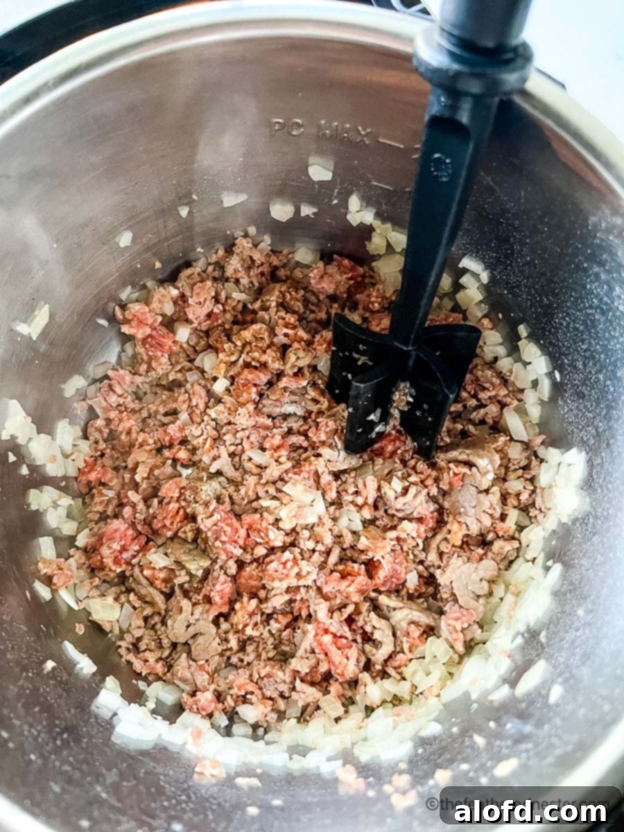 Instant Pot Creamy Tortellini Soup 6 Browning meat in pot of ground Italian sausage soup with pasta.