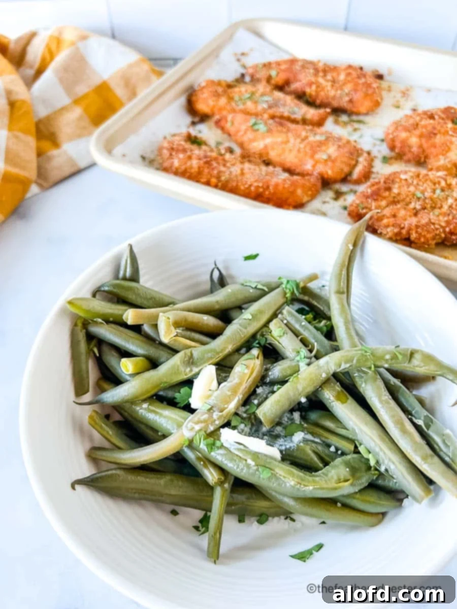 Quick and Tender Instant Pot Green Beans 2 Instant pot green beans on a bowl with shake and bake chicken tenders and yellow cloth in the background.