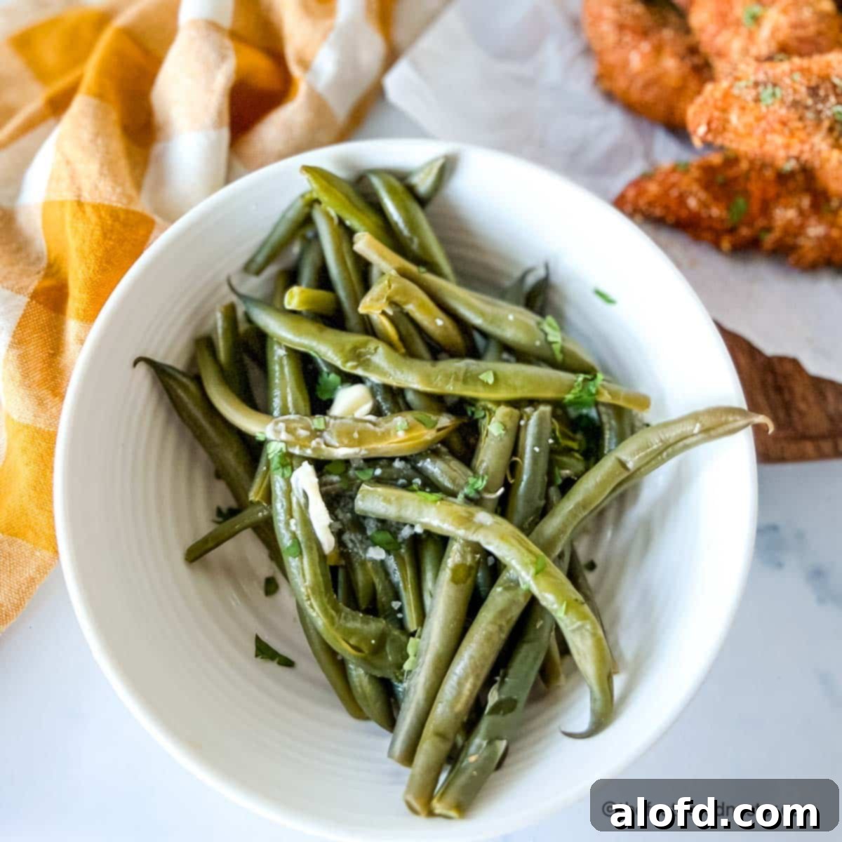 Quick and Tender Instant Pot Green Beans 3 Instant pot fresh green beans in a bowl with shake and bake chicken tenders and yellow cloth in the background.