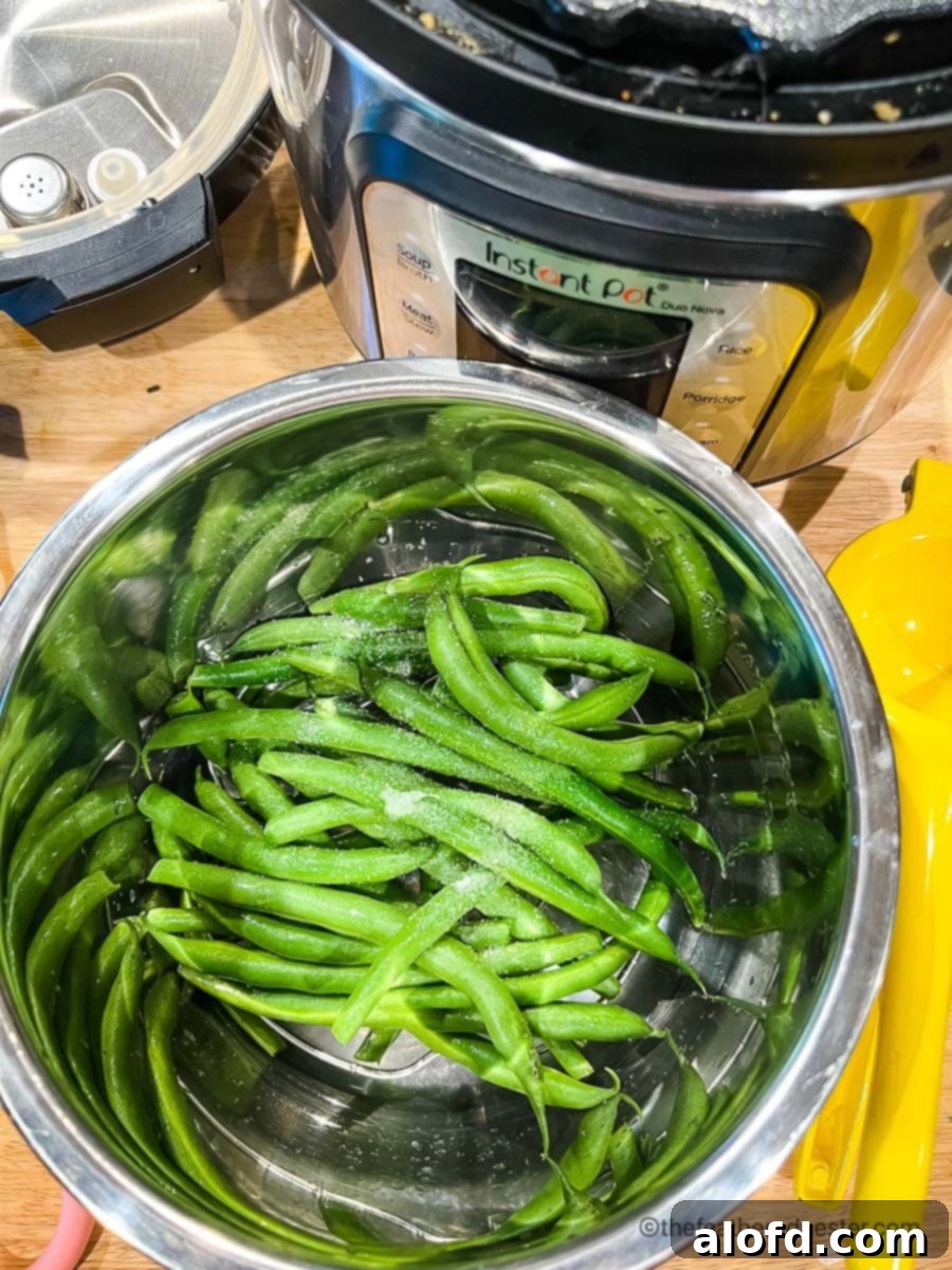 Quick and Tender Instant Pot Green Beans 5 Fresh green beans with salt on a steaming basket with instant pot in the background.