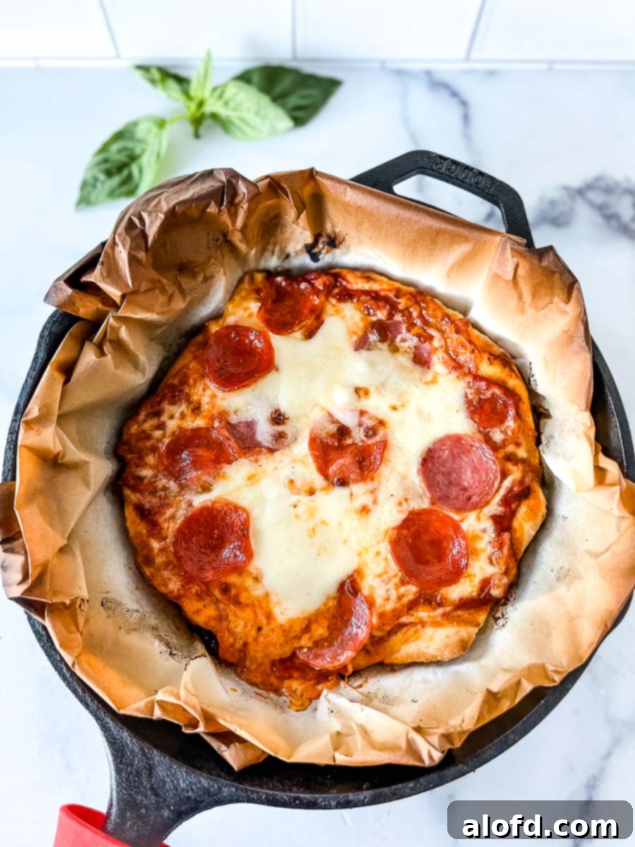Flame-Kissed Pizza 11 Freshly grilled pizza in a cast iron skillet on parchment paper, adorned with fresh basil.