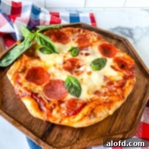 Flame-Kissed Pizza 14 A fire grilled pizza on a wooden serving tray with a sprig of basil and a red, white, and blue napkin in the background.
