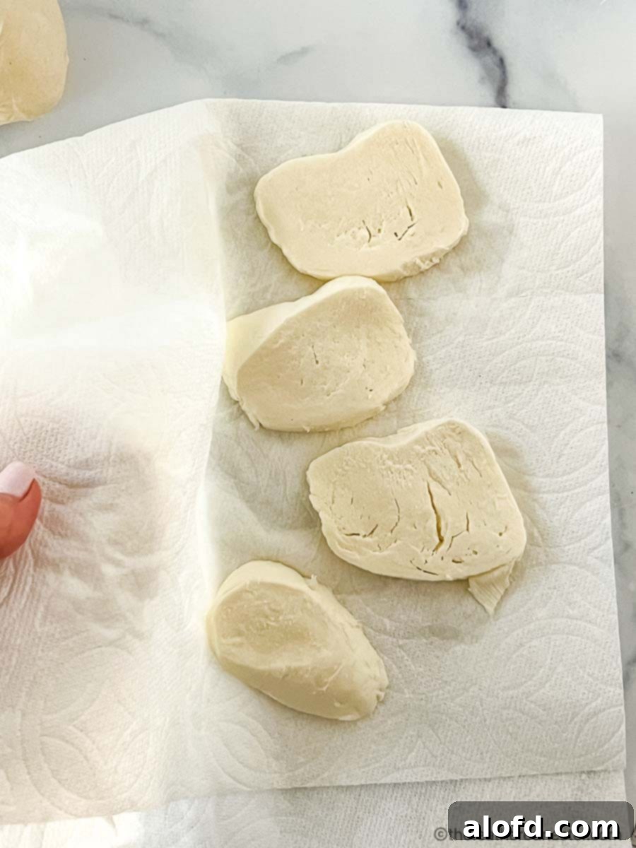 Flame-Kissed Pizza 9 Blotting fresh mozzarella cheese slices between paper towels to remove excess moisture for pizza.