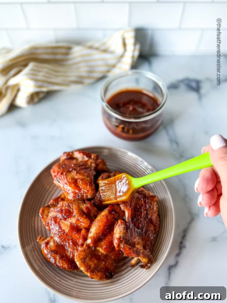Basting 3 Ingredient BBQ Sauce on chicken on a plate.