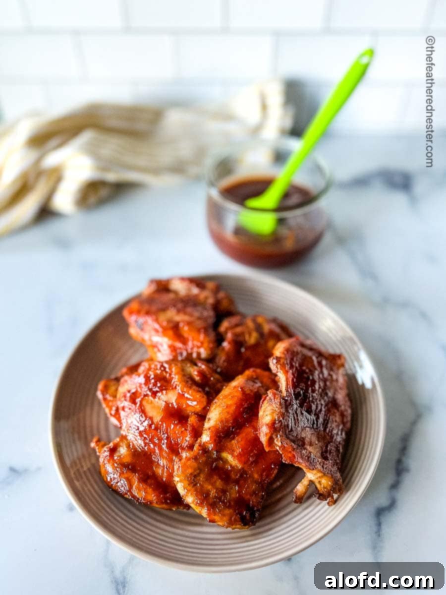 Chicken on a plate with 3 Ingredient Homemade BBQ sauce on a medium bowl with a basting brush.