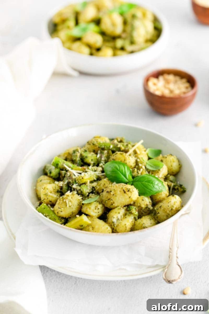 Two plated servings of potato pasta on a white background, garnished with fresh basil.