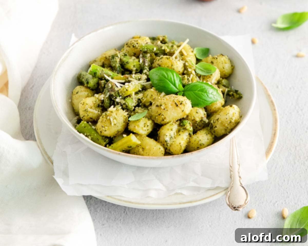A beautiful white bowl of potato pasta with fresh asparagus, ready to be enjoyed.