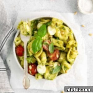 Pesto Tortellini Perfection 10 Bowl of cold pesto tortellini salad with a fork placed on top.