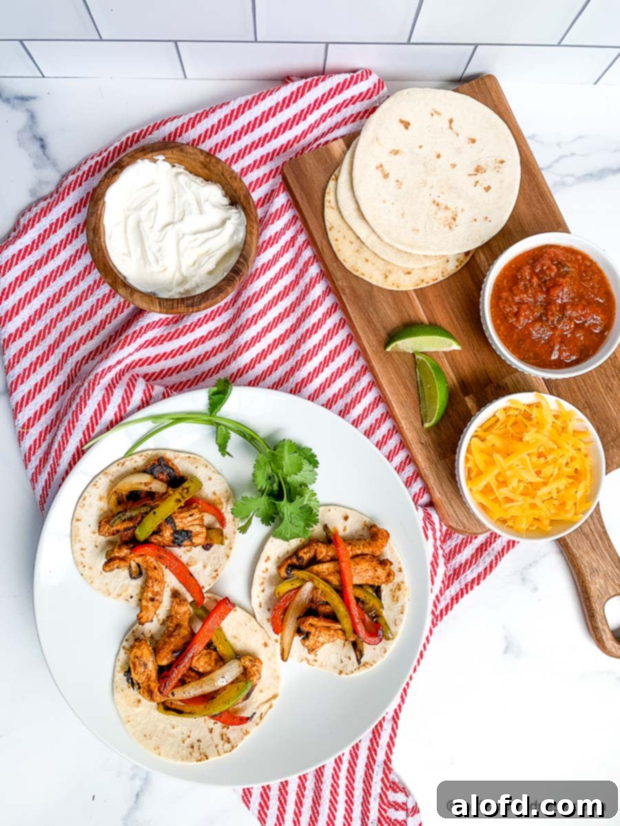 A vibrant plate featuring three perfectly cooked chicken fajitas, nestled in soft flour tortillas. The fajitas are garnished with fresh cilantro and served on a crisp red and white napkin. This image captures the delicious appeal of Blackstone Chicken Fajitas, highlighting their tender, flavorful chicken and colorful vegetables, ideal for an easy and satisfying meal cooked on your Blackstone Griddle.