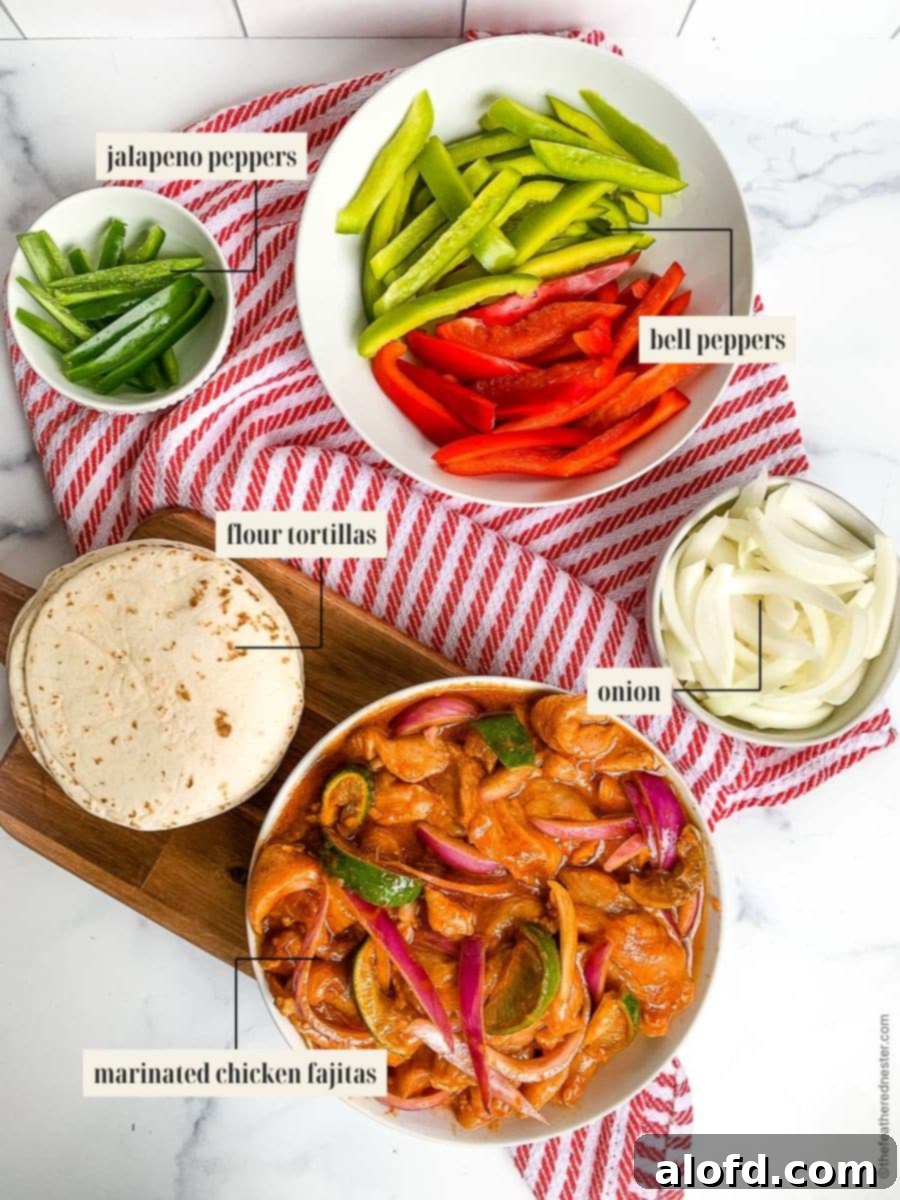 A selection of fresh ingredients for Blackstone fajitas including sliced jalapeno, bell peppers, onions, a stack of flour tortillas, and a bowl of marinated chicken, all arranged on a wooden board over a festive red and white cloth.