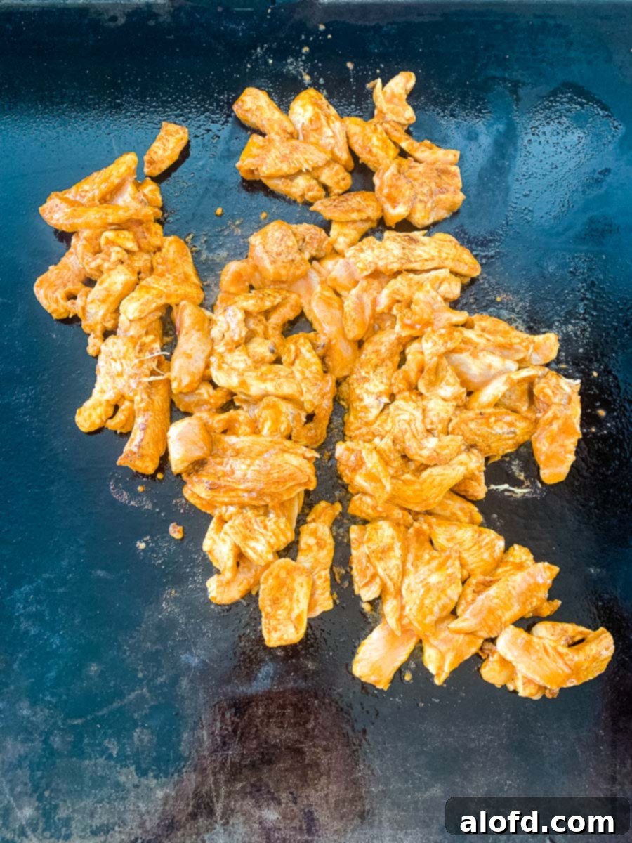 Marinated chicken fajitas searing on a hot flat griddle, developing a delicious char and locking in juices.