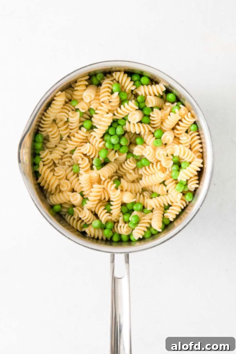 Spring Pea Pasta 8 Rotini pasta and bright green peas cooking together in a large stock pot of boiling water.