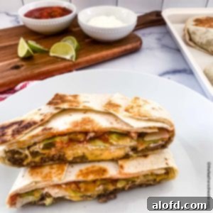 Blackstone's Ultimate Crunchwrap 10 A perfectly cooked copycat crunchwrap, sliced in half to reveal its layers, presented on a white plate. In the background, a serving board holds bowls of sour cream, salsa, a bottle of Tapatio, and fresh lime slices, ready for customization.