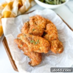 shake and bake chicken tenders placed on a parchment paper on top of a wood serving plate.