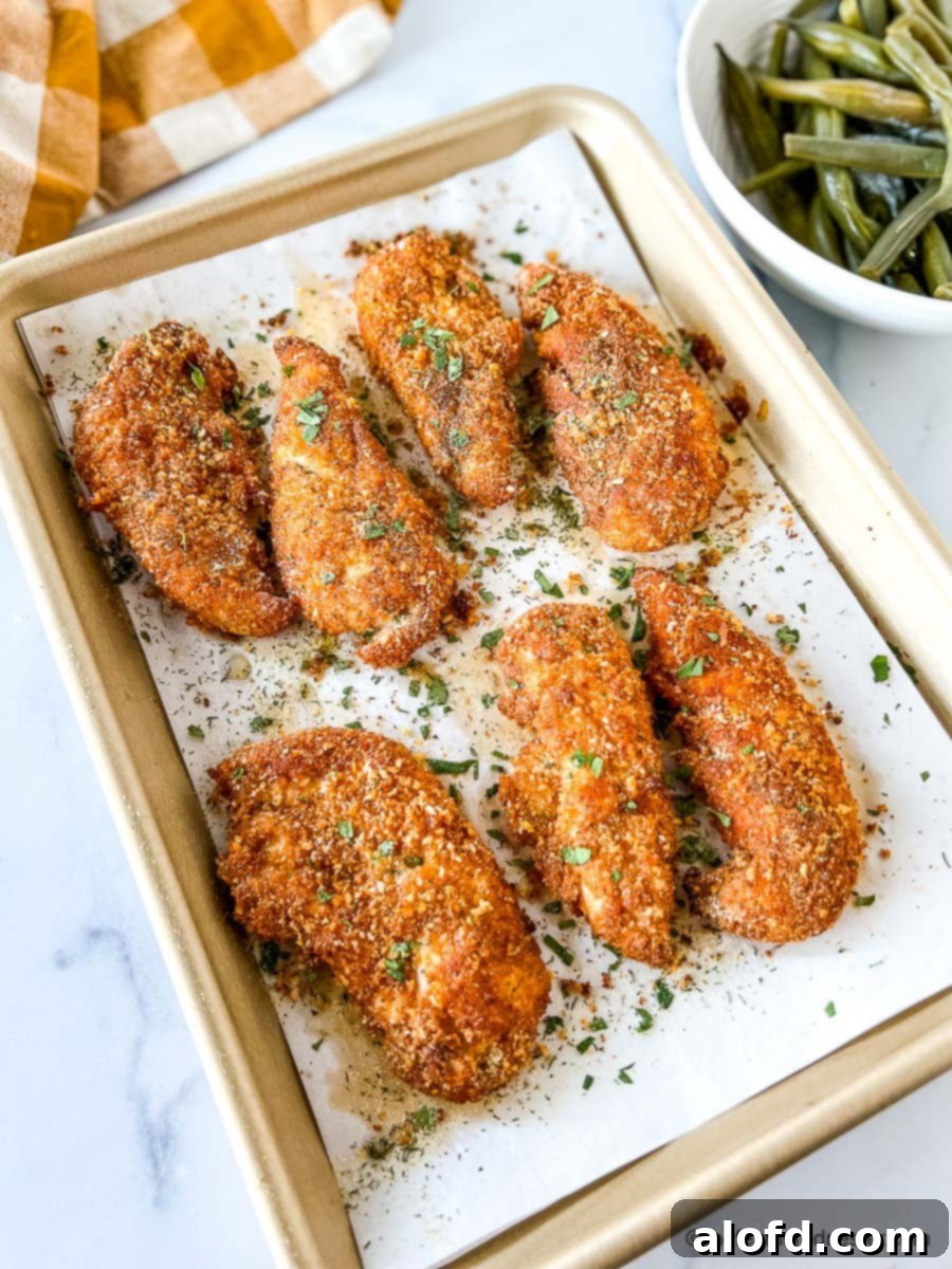 Crispy baked panko chicken tenders on parchment lined baking pan.