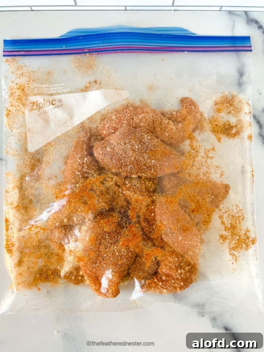 Seasonings and chicken tenderloins mixed inside of a ziploc bag.