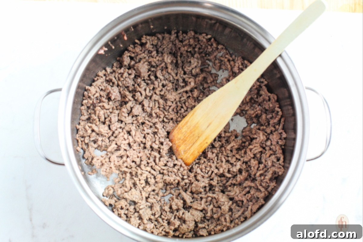 Hearty Skillet Chili 5 Browning ground beef in a pot on stove top.