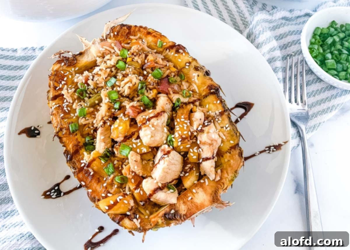 A serving of Hawaiian chicken fried rice beautifully glazed with teriyaki sauce, presented within a pineapple bowl.