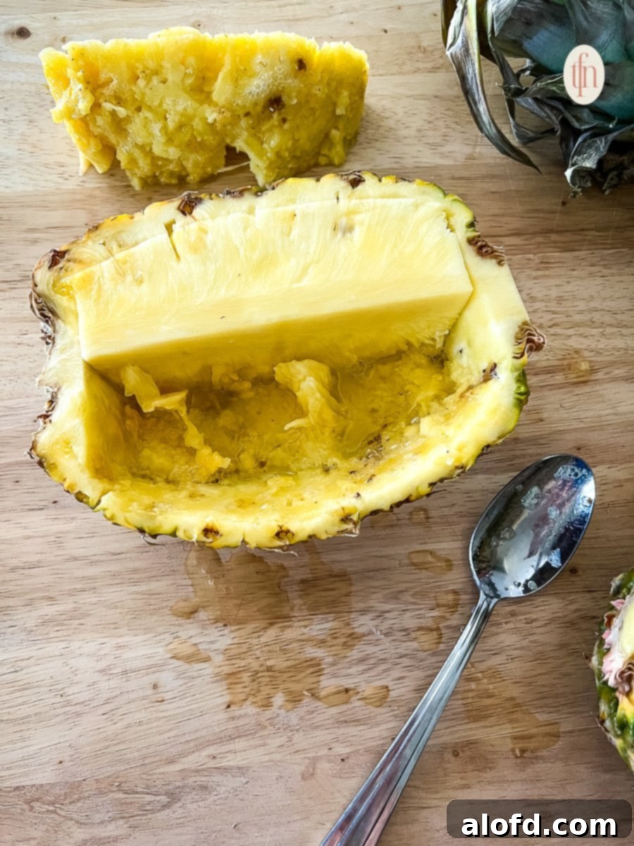 A partially hollowed pineapple bowl, with some fruit remaining, ready for the next step.