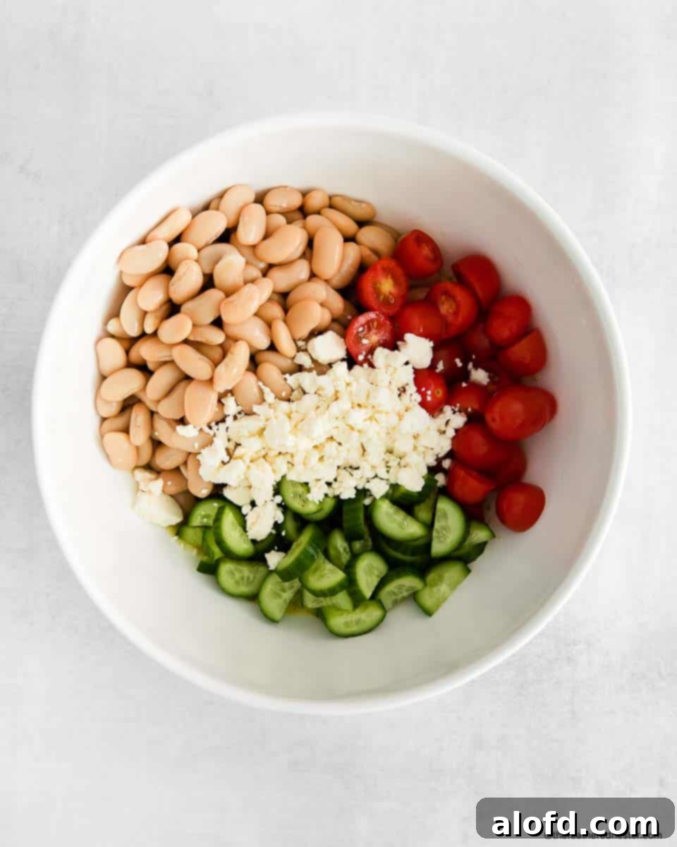Vibrant Italian Bean Medley 7 Fresh cannellini beans, cherry tomatoes, cucumbers, and feta cheese in a white bowl before dressing.
