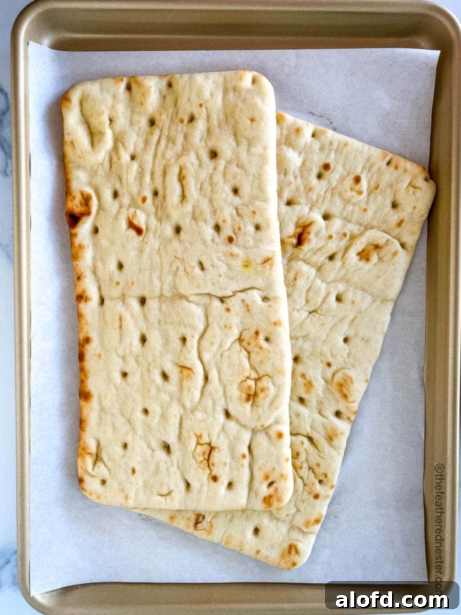 Classic Margherita Flatbread 5 A parchment-covered baking sheet with two unbaked flatbread pizzas, ready for toppings.