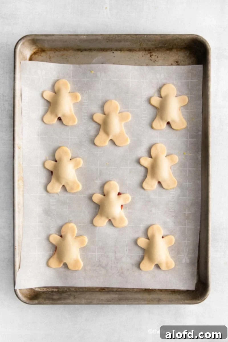 mummy pie pastry cut outs on a parchment lined baking sheet ready to bake