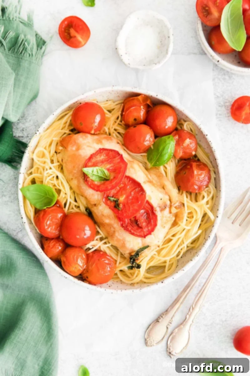 One Pan Caprese Chicken 4 A bowl of chicken pasta with roasted cherry tomatoes and basil on top.