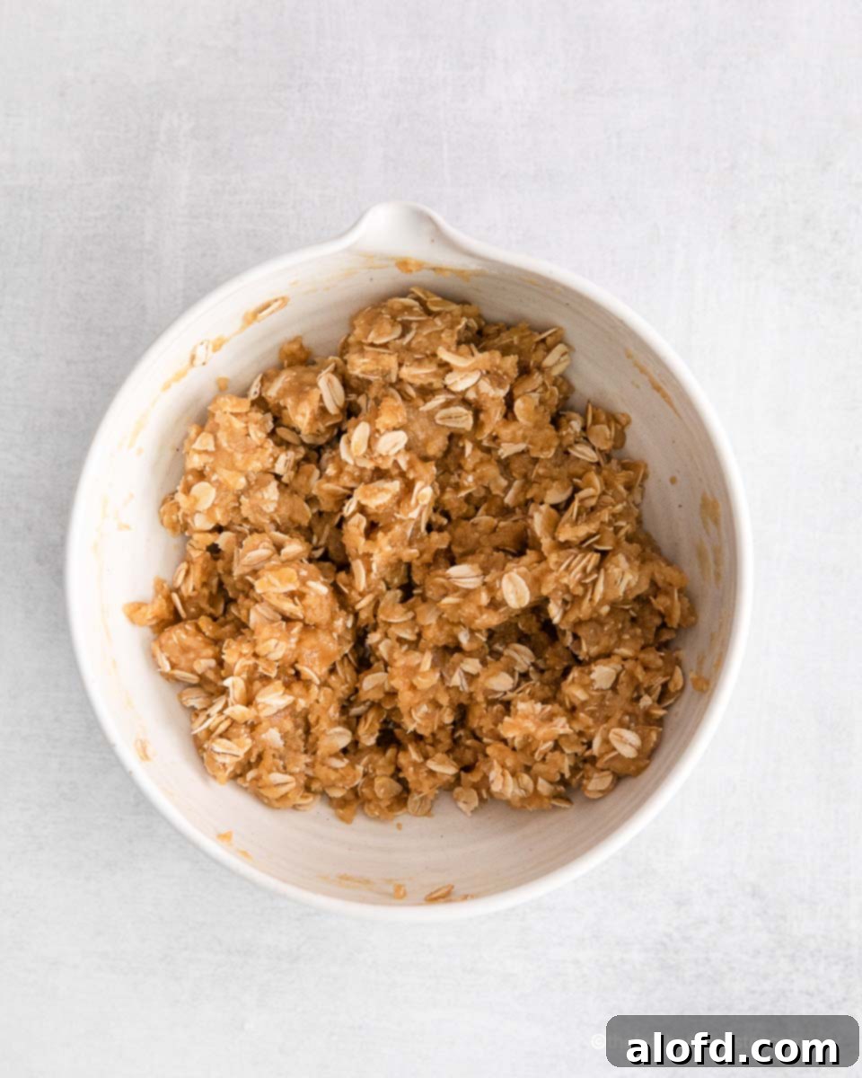 Oat crumble topping mixture in a small bowl, showing its crumbly texture.