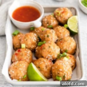 Sweet chili meatballs with slices of lime placed in a baking sheet, garnished with fresh cilantro.