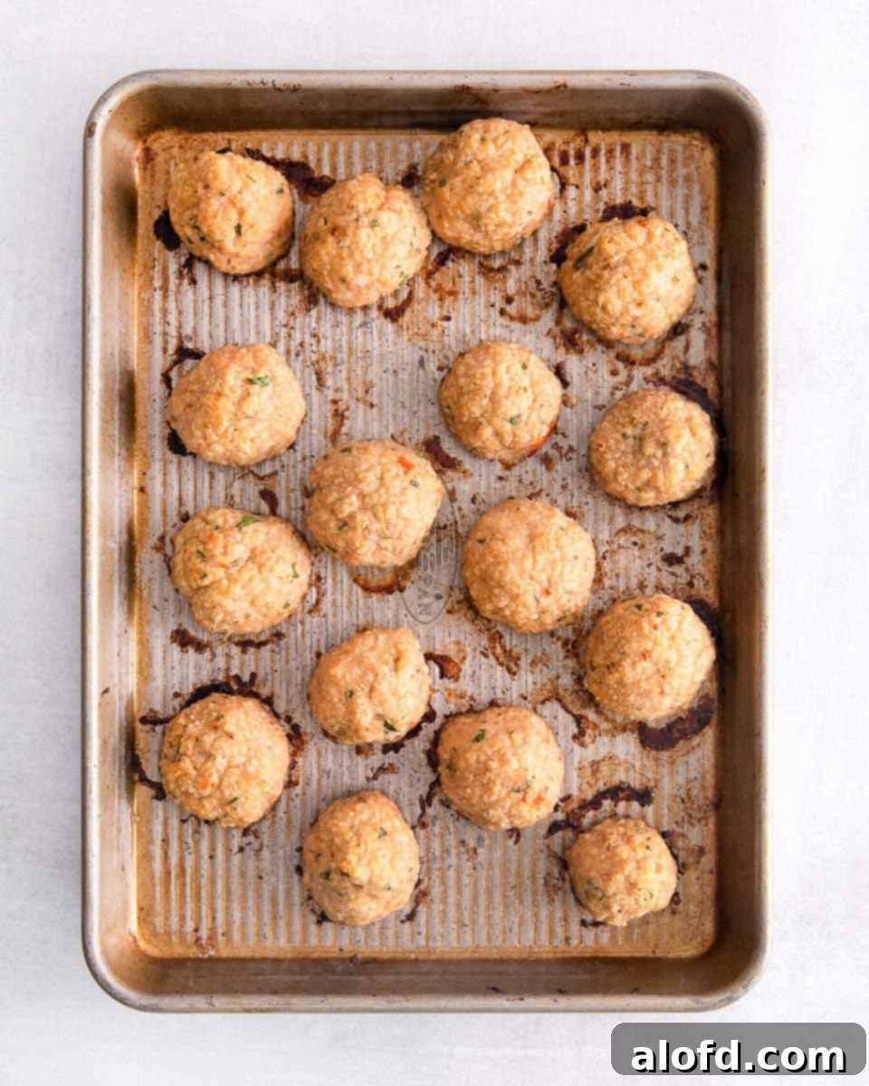 A baking sheet filled with freshly baked, golden sweet chili meatballs, glistening with a hint of oil.