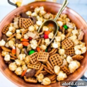 Monster Munch Mix 8 A large copper bowl of M&M Halloween snack mix, with a golden scoop nestled inside, and a gold and white napkin in the background.